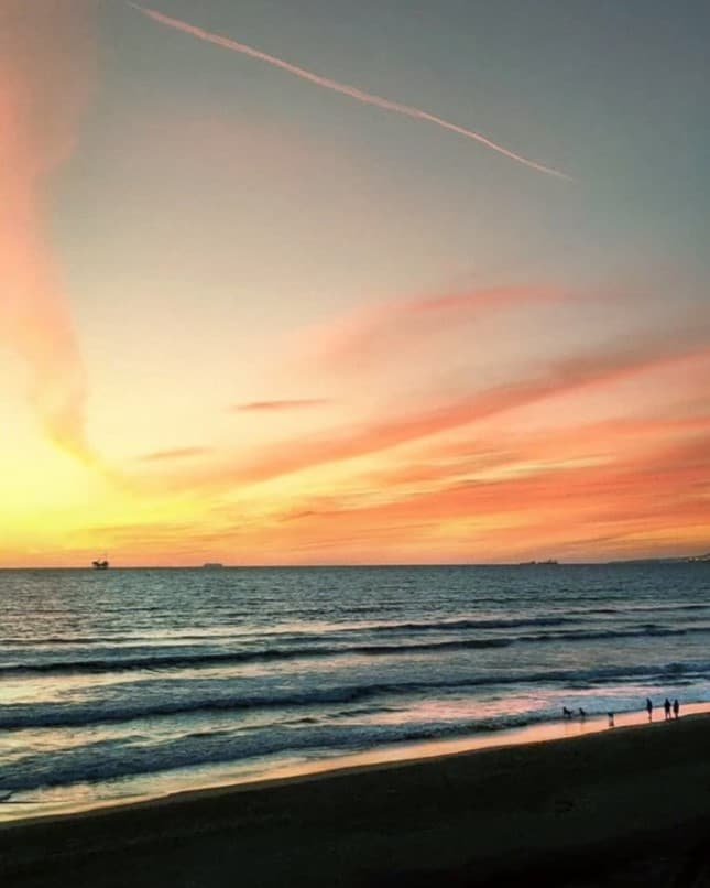 Landscape photo taken during golden hour for dreamy atmosphere Beach with people walking by the sand during golden hour ambient light.