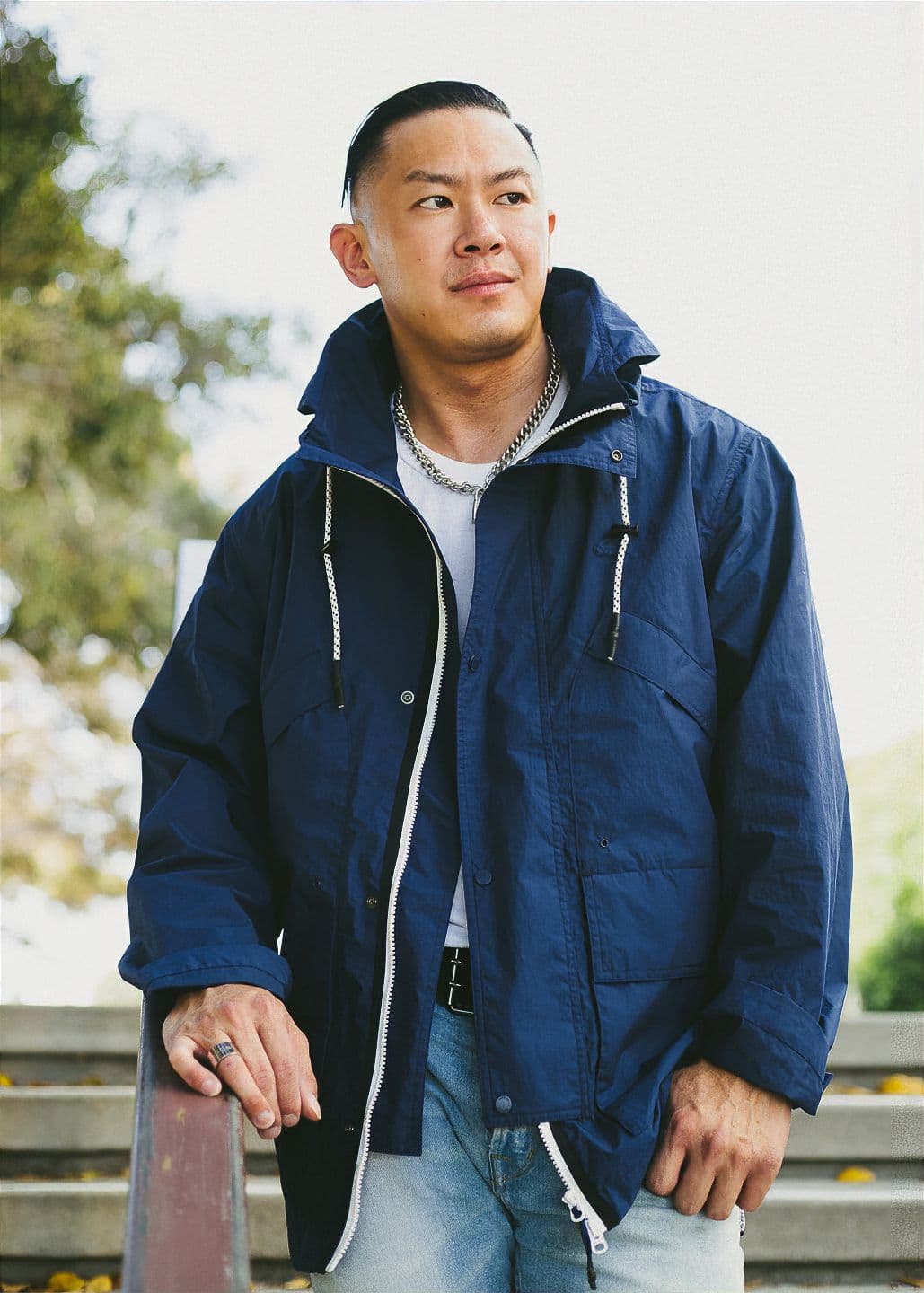 Portrait using natural ambient light Man standing on top of staircase wearing rain jacket.