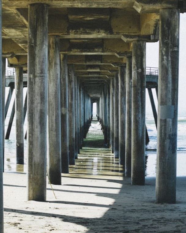 Frame within a frame Columns lined up in a row under the pier.